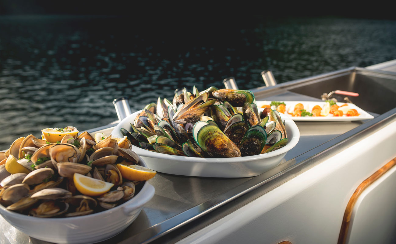 Guests enjoying fresh seafood and local wine aboard a cruise through the Marlborough Sounds, South Island New Zealand
